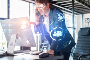 Businessman in suit has conference call to hire new employees for international business consulting. HR, social media hologram icons and interconnections over office background with panoramic windows