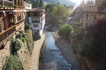 River crossing a medieval village at sunset with a ray of sunlight.