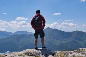 A mountaineer on top of a mountain on his back with a backpack enjoying the scenery