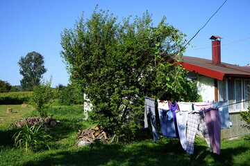 Bunte Wäsche auf der Wäscheleine im Sommer auf dem Lande bei blauem Himmel und Sonnenschein in...