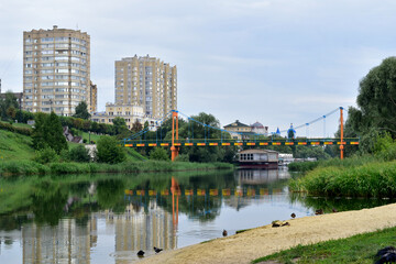 Two high-rise buildings are reflected on the surface of the river on the bank that they stand on.