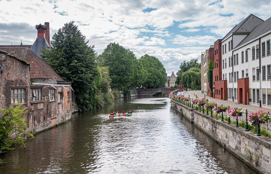 Gent, Flanders, Belgium - July 30, 2021: Sint Antoniuskaai along Lieve river looking at Rabot fortification under blue cloudscape. Houses on both sides of dark light reflecting water.