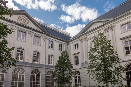 Gent, Flanders, Belgium - July 30, 2021: White palacial buidling and courtyard of Art Academy under blue cloudscape with some green foliage.