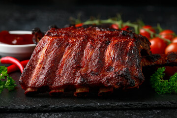Grilled pork ribs with bbq sauce and herbs on stone board