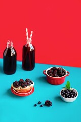 Healthy breakfast toast with cheese, blackberries and blueberries and berry juice on a bright colored background. The concept of a modern still life.