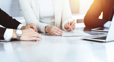 Business people discussing contract while working together in sunny modern office. Unknown businessman and woman with colleagues or lawyers at meeting - obrazy, fototapety, plakaty