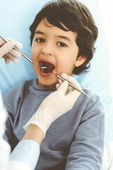 Little arab boy sitting at dental chair with open mouth during oral checking up with dentist doctor. Stomatology concept