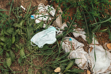 Used disposable medical mask of personal protection on a pile of rubbish in the forest
