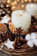 Obraz na płótnie Canvas Rustic decor for christmas holiday family dinner. Center piece with white candle, dry orange, cones, cotton. Zero waste eco friendly home decoration. Cozy atmosphere, wooden background. Close up
