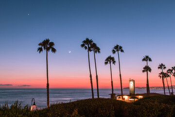San Clemente, California sunset landscape with palm trees and a moon overlooking the ocean.