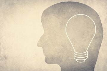 Silhouette of a face with a lightbulb, textured background, empty copy space for text