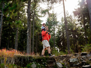 Young man carry on shoulders ihis son in a forest