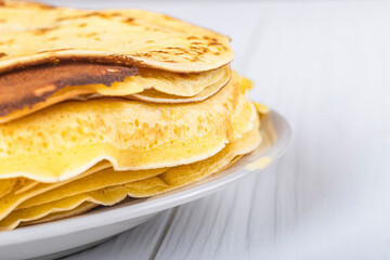 white wooden background in retro style. the plate in it is thin yellow pancakes. close-up.