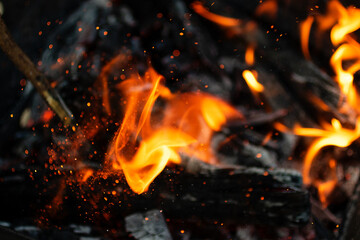Defocused closeup photography of burning flame with sparkles.Burning bonfire. A picnic concept in nature.Selective focus.Blurred background,good as overlay layer.