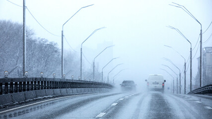 Heavy snowfall and poor visibility on the road.