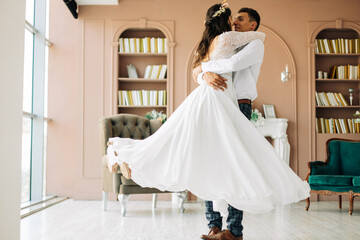 Naklejka premium Happy wedding couple, attractive bride and groom hug each other, the groom hugs and holds the bride in his arms and circles her