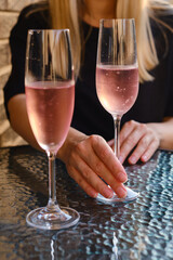 A glass of rose wine in the hands of a girl relaxing on restaurant terrace. Summer holiday. Celebrate and enjoy moment. Alcoholic drink tasting. Romantic evening aperitif. Wine glass closeup