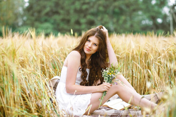 Portrait of pretty woman in summer outfit holding bouquet of flowers in field, horizontal image
