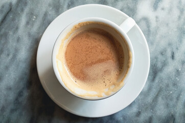 half full cup of cappuccino or coffee close up on grey marble stone background