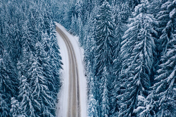Road in the winter mountain forest. Drone view.