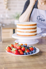 A girl decorates a cake with custard