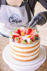 the process of decorating a cake with fresh berries, strawberries, blueberries