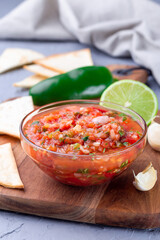 Tex-Mex cuisine salsa Asada sauce with roasted vegetables, served with tortilla chips and lime, vertical