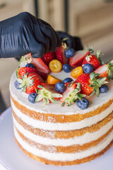 the process of decorating a cake with fresh berries, strawberries, blueberries
