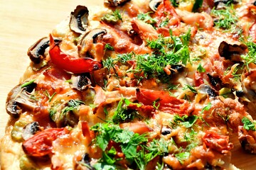 pizza of champignons, tomato, ham, sausages, sprinkled with parsley and homemade dill close-up