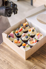 The girl decorates cupcakes with berries, fruits, chocolate