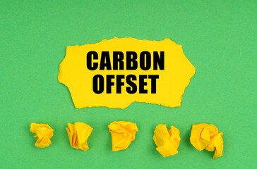 On a green background, crumpled yellow paper and a sheet with the inscription -Carbon offset