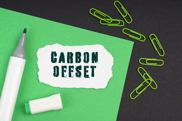 On a black background, a marker, paper clips, a sheet and torn paper with the inscription -