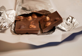 broken hazelnut chocolate close up on white background - swiss chocolate broken in pieces on white background