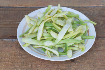 Green beans in a plate ready for cooking - Wooden background