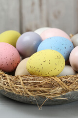 Bowl with Easter eggs on wooden table.