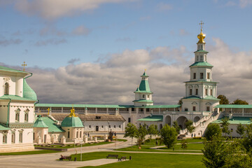 Fototapeta na wymiar historical white-stone architecture of the New Jerusalem Monastery against the background of a dramatic blue sky with white clouds on a sunny summer day in Istra Moscow Region