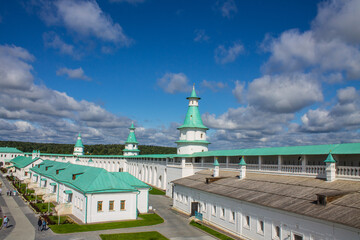 historical white-stone architecture of the New Jerusalem Monastery against the background of a dramatic blue sky with white clouds on a sunny summer day in Istra Moscow Region