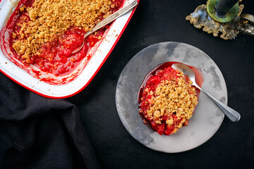 Modern style traditional American crumble cake with rhubarb and apple with backed topping served as top view on a design plate and backing form