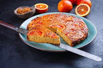 Modern style traditional Italian blood orange ricotta pie with fruits and almonds served as close-up on a Nordic design plate with copy space