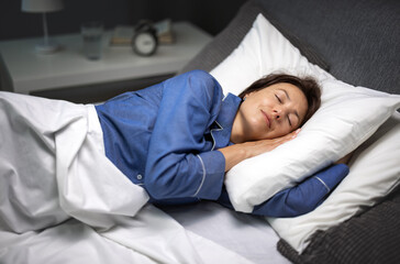 Pleasant mature woman sleeping peacefully on cozy comfortable bed with soft linen. Caucasian lady...