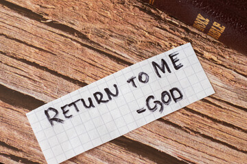 Return to God Jesus Christ. A handwritten quote on wooden background with a Holy Bible Book. The...