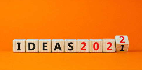 2022 ideas new year symbol. Turned a wooden cube and changed words 'Ideas 2021' to 'Ideas 2022'. Beautiful orange background, copy space. Business, 2022 ideas new year concept.