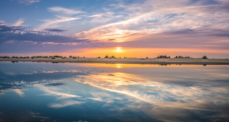 Obraz premium Colorful sunset over the Baltic sea from the pine forest viewpoint. Cloud reflections in calm water.