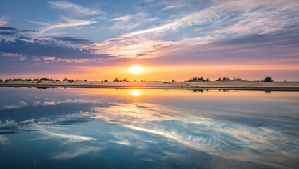 Obraz premium Colorful sunset over the Baltic sea from the pine forest viewpoint. Cloud reflections in calm water.