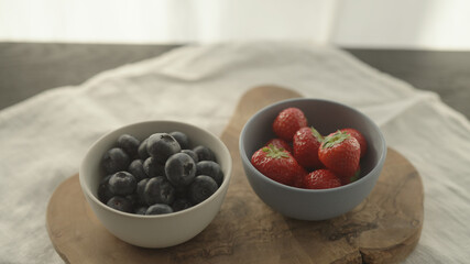 fresh blueberries and strawberries in ceramic bowls with natural light
