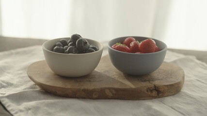 fresh blueberries and strawberries in ceramic bowls with natural light