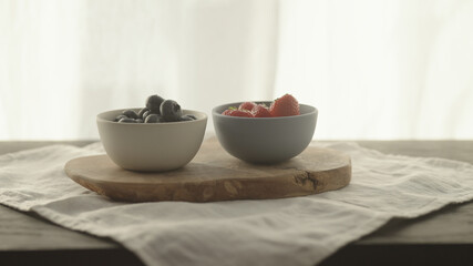 fresh blueberries and strawberries in ceramic bowls with natural light