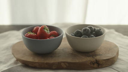 fresh blueberries and strawberries in ceramic bowls with natural light