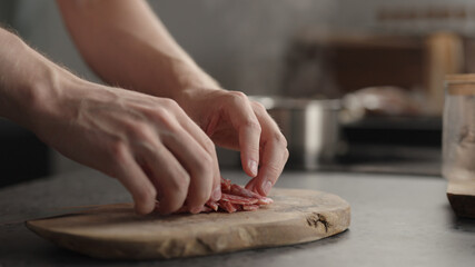 Fototapeta na wymiar man arrange choped salami on olive board