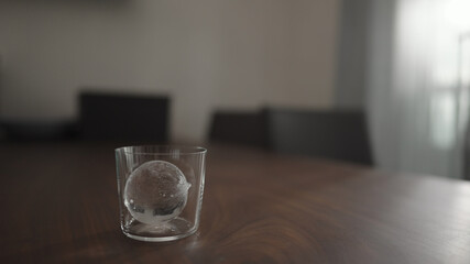 ice ball into tumbler gllass on walnut table